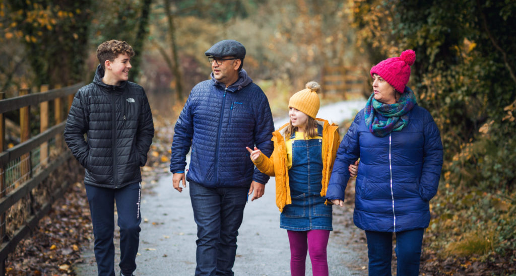 Two adults and two children walking in the woods
